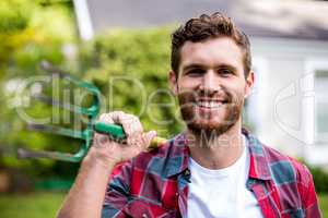 Portrait of man with rake standing in yard