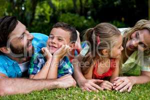 Happy parents lying with children in yard