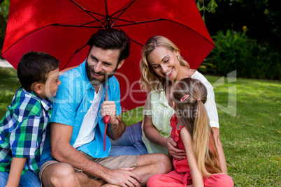 Family with umbrella sitting on grass at yard