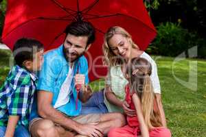 Family with umbrella sitting on grass at yard