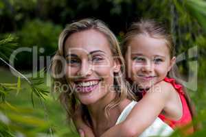 Smiling mother carrying daughter in yard