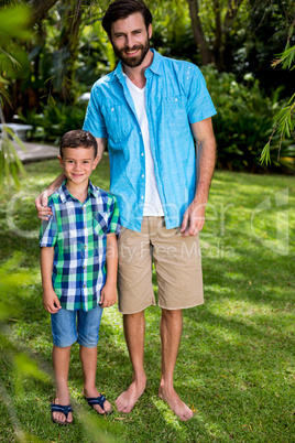 Father and son standing on grass in yard