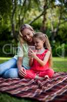 Smiling daughter showing phone to mother in yard