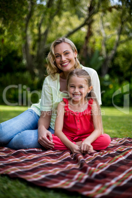 smiling mother and daughter sitting in yard