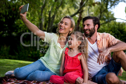 Woman taking selfie with husband and daughter at yard