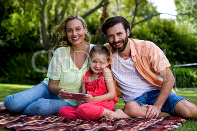 Smiling family with mobile phone sitting in yard