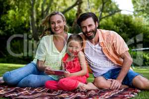 Smiling family with mobile phone sitting in yard