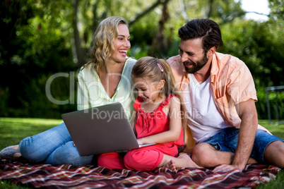 Parents with daughter using laptop at yard
