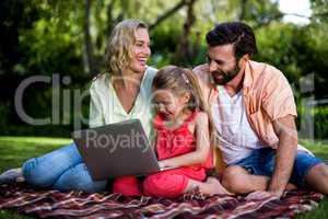 Parents with daughter using laptop at yard