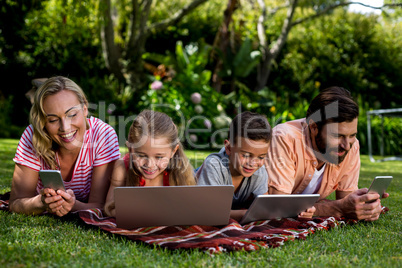 Family using technologies while lying at yard