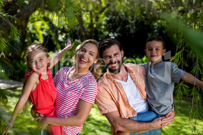 Happy parents carrying smiling children at yard