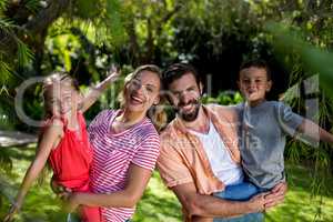 Happy parents carrying smiling children at yard