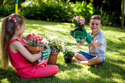 Siblings holding flower pots in yard