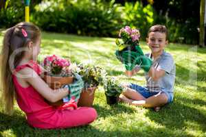 Siblings holding flower pots in yard