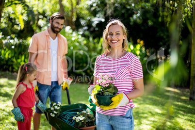 Woman holding flower pot with family at yard