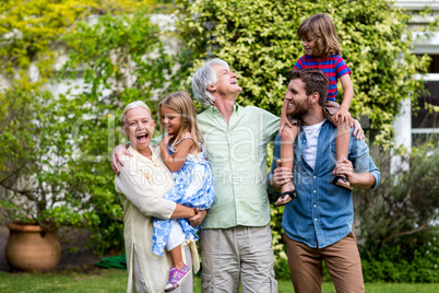 Grandparents with grandchildren and son standing in yard