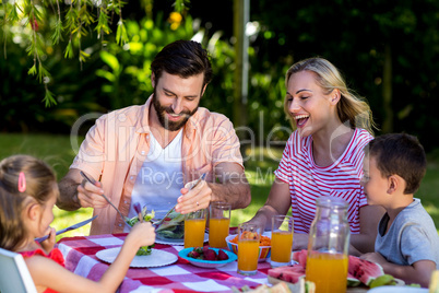 Family enjoying breakfast at table in yard