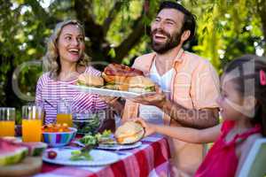 Couple with sandwiches at table in yard