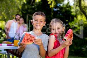 Siblings holding watermelon with parents at yard
