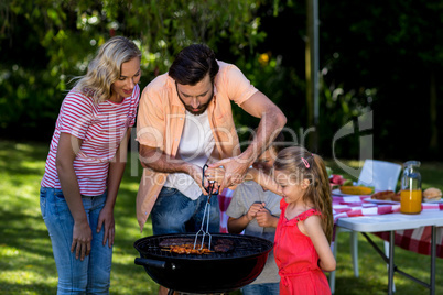 Father with mother teaching children to barbecue food