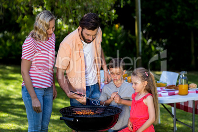 Family grilling food at barbecue in yard