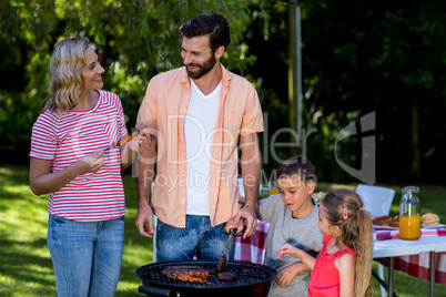 Mother and father with children cooking food at barbecue