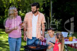 Mother and father with children cooking food at barbecue