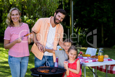 Family cooking food on barbecue grill at yard