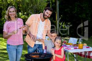 Family cooking food on barbecue grill at yard