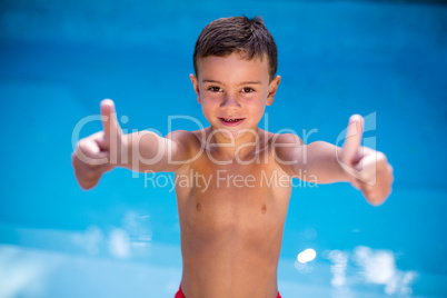 Shirtless boy gesturing at swimming pool