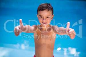 Shirtless boy gesturing at swimming pool