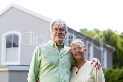 Senior couple standing in yard against house