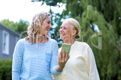 Granddaughter looking at grandmother while using phone