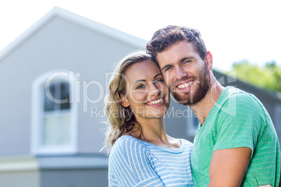 Smiling couple standing against house
