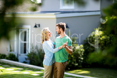 Couple dancing in yard against house