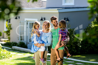 Smiling parents carrying children in yard