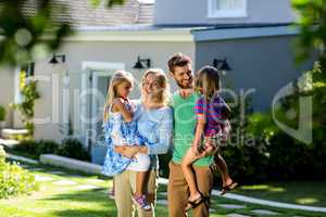 Smiling parents carrying children in yard