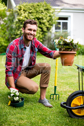 Happy gardener holding potted plants in yard