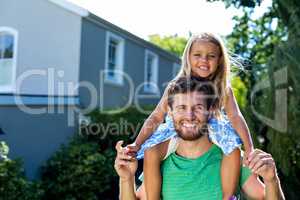 Father carrying daughter on shoulders in yard