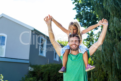 Portrait of father carry daughter on shoulders in yard