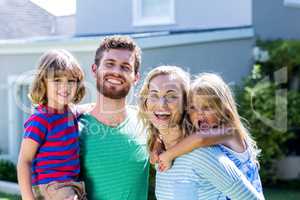 Smiling family standing against house