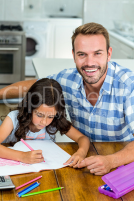 Happy father with daughter writing in book at home