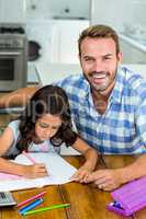 Happy father with daughter writing in book at home
