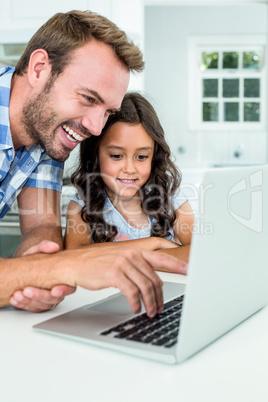 Man with daughter using laptop computer at home