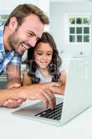 Man with daughter using laptop computer at home