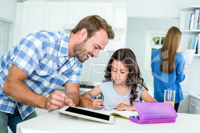 Happy father assisting daughter in homework at home