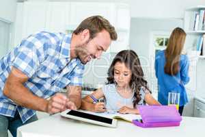 Happy father assisting daughter in homework at home