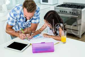 Father assisting daughter in doing homework