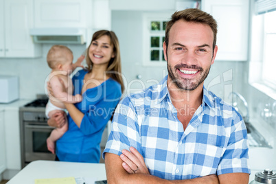 Smiling man with family in background at kitchen