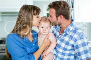 Parents kissing baby boy at home